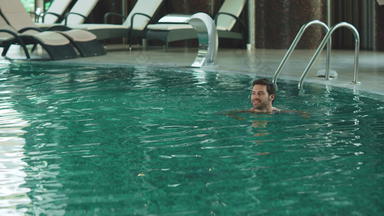 快乐男人。游泳现代酒店假期英俊的男人。洗澡池